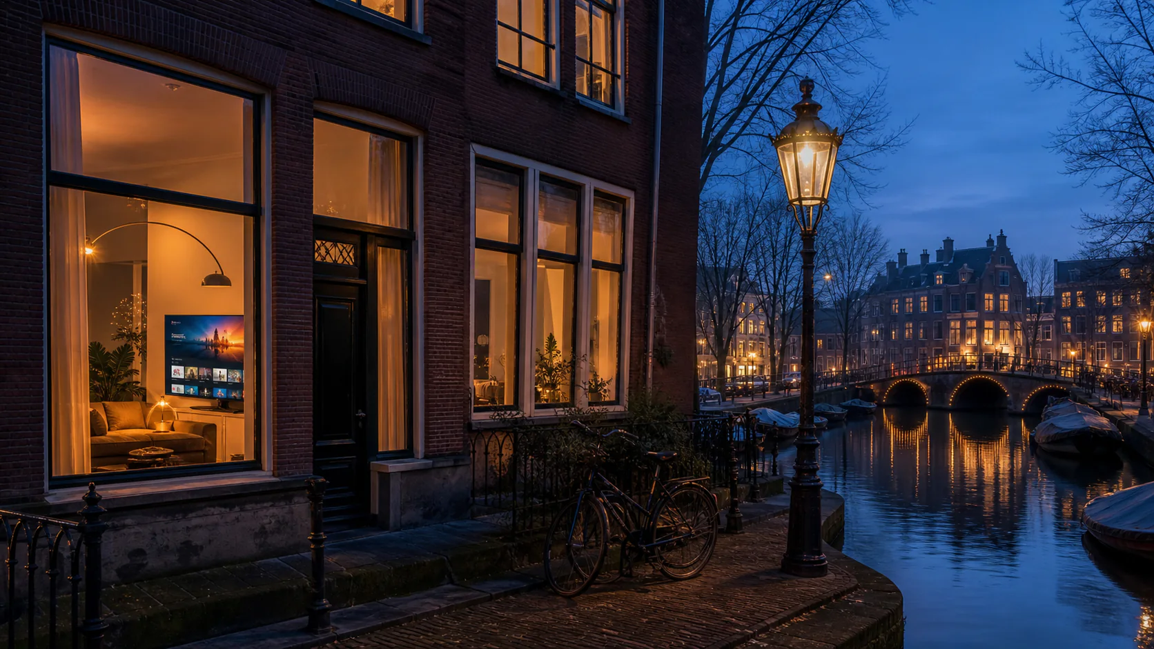 Verlichte Nederlandse grachtenwoning waar in de avond televisie wordt gekeken